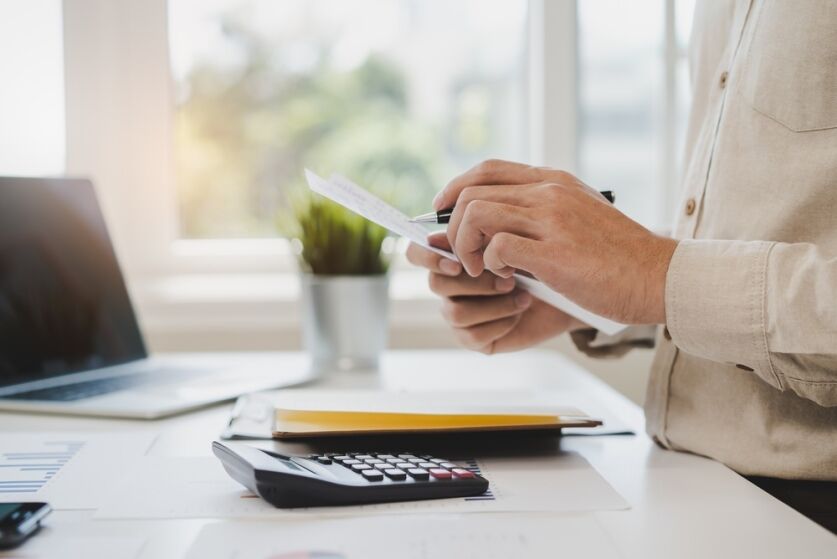 Deduction planning, debt asian accountant hand using calculator to calculating money balance from bill and income, cost budget expenses for pay money form personal individual on table at home.