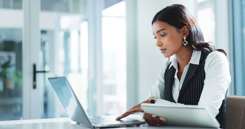 Office, serious and business woman on laptop for insurance, risk management or policy sales on internet. Technology, tablet or employee reading email for financial coverage, review claims or research