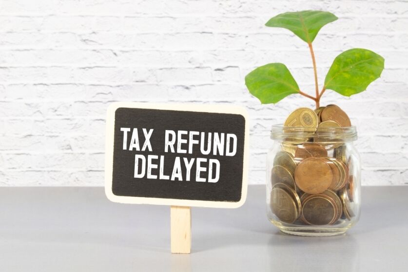 Sticky note with the text Tax Refund Delayed on Income Tax form background with calculator