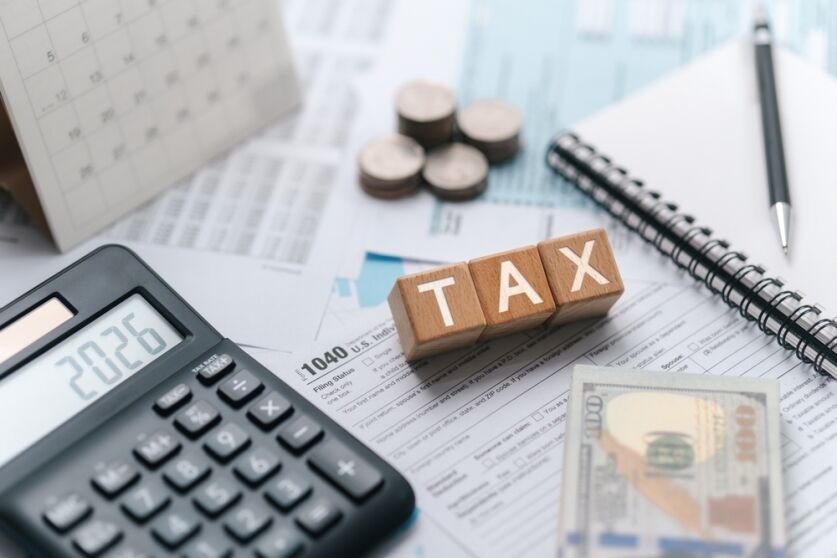 Tax planning concept for 2026. Wooden blocks with the word tax. Calculator on phone. Interest, Financial calculations, Tax law, Tax payment, Government taxes and budget planning.