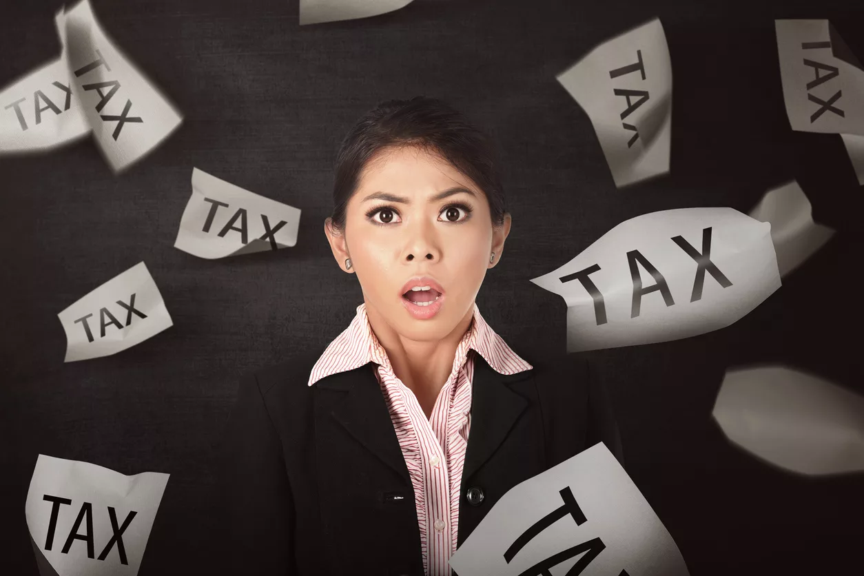 Business woman stressed IRS launches ERC audit program displayed with falling paper with Tax text on blackboard background