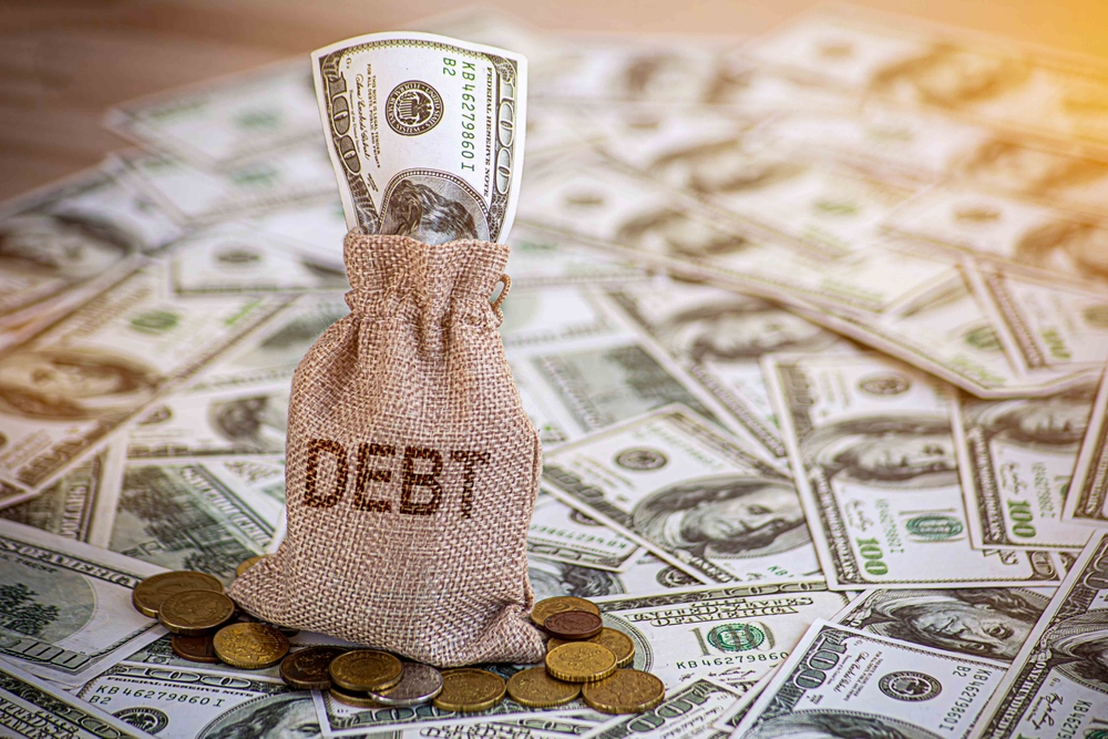Financial debt concept. A man hand on stack of coins and money bag showing about debt.
