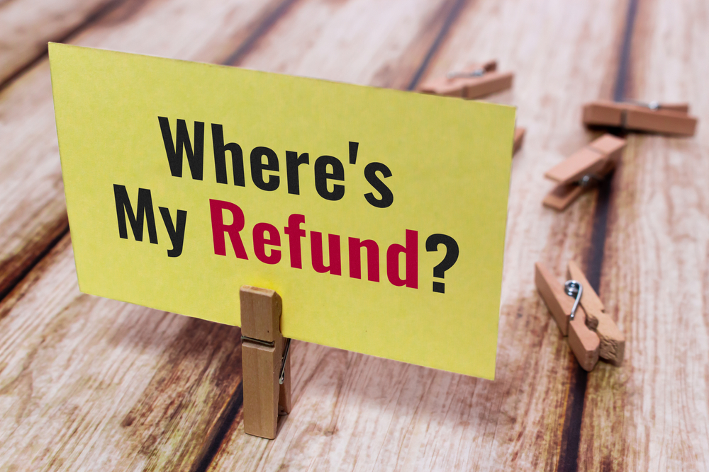 Conceptual message card showing Where is My Refund on shabby wooden table. Nice wooden clothespin or natural wooden pinch holding yellow paper note. Concept of business, economy and finance