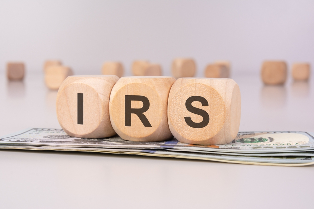 IRS wooden blocks on cash stack, representing US taxes.